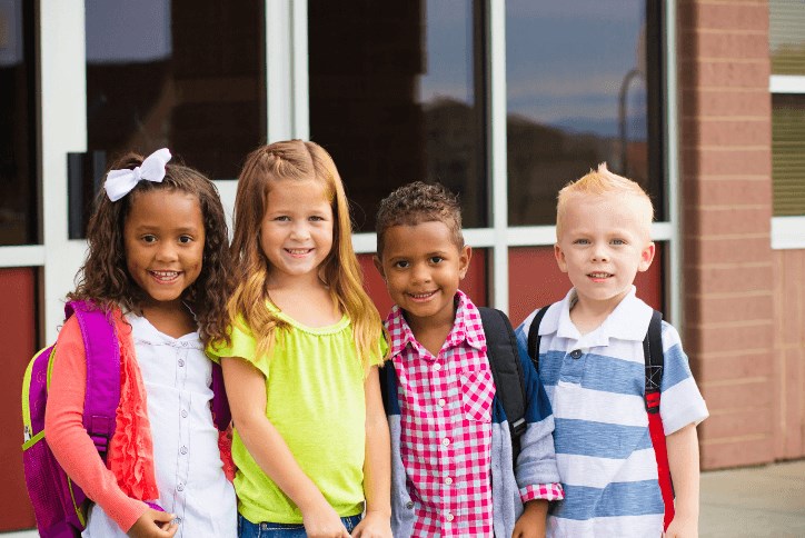 Four kids standing outside a school