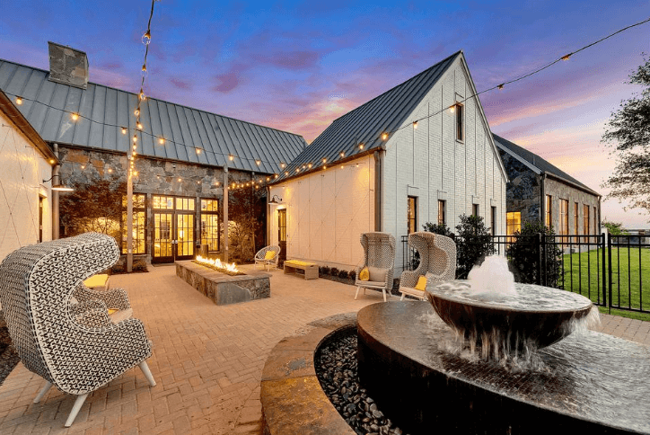 Exterior of The Grove Frisco Welcome Center with water fountain, large wicker chairs and fire