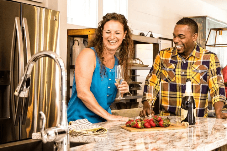 Woman and man enjoying fresh strawberries and a glass of champagne in a modern kitchen