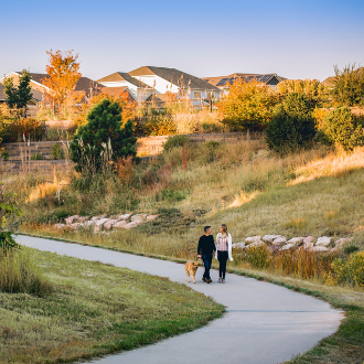 Couple with a dog walking on a paved trail in Inspiration Colorado